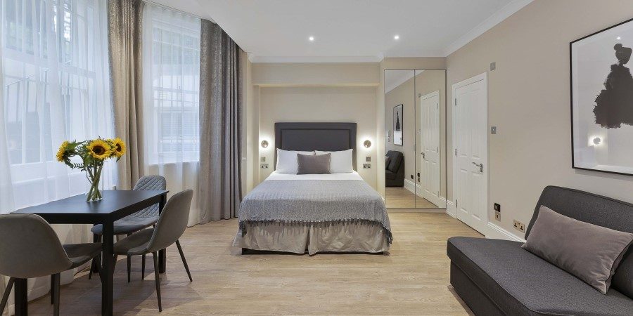 A well-furnished hotel room displaying a bed, a couch, and a table, designed for relaxation and comfort.